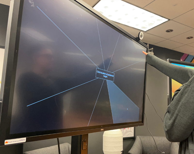 UFOV_Touchscreen A person pointing at a large screen in an office