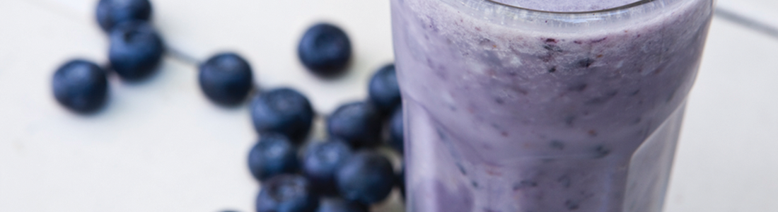 bluenana A blueberry smoothie in a tall glass next to blueberries