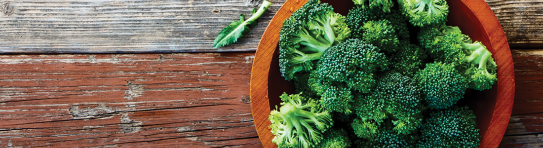 broccoli A wooden bowl filled with broccoli on top of a wooden table
