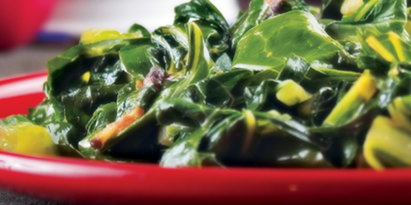 collardgreens A red bowl filled with greens on top of a table