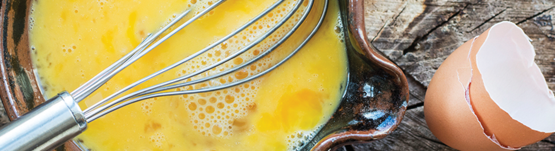 egg A bowl with eggs and a whisk on a wooden table