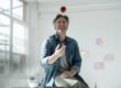 A man sitting on top of a table with an apple on top of his head