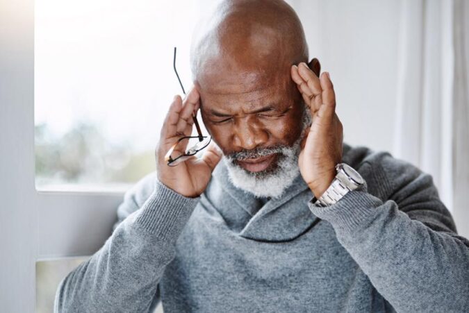 A man with a bald head holding his hands to his ears